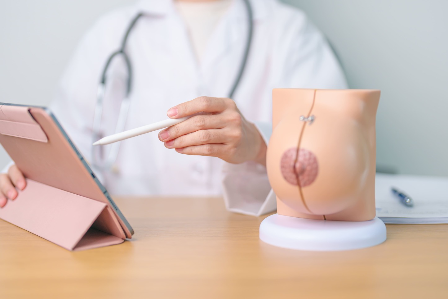 a surgeon points at a digital tablet while explaining breast anatomy